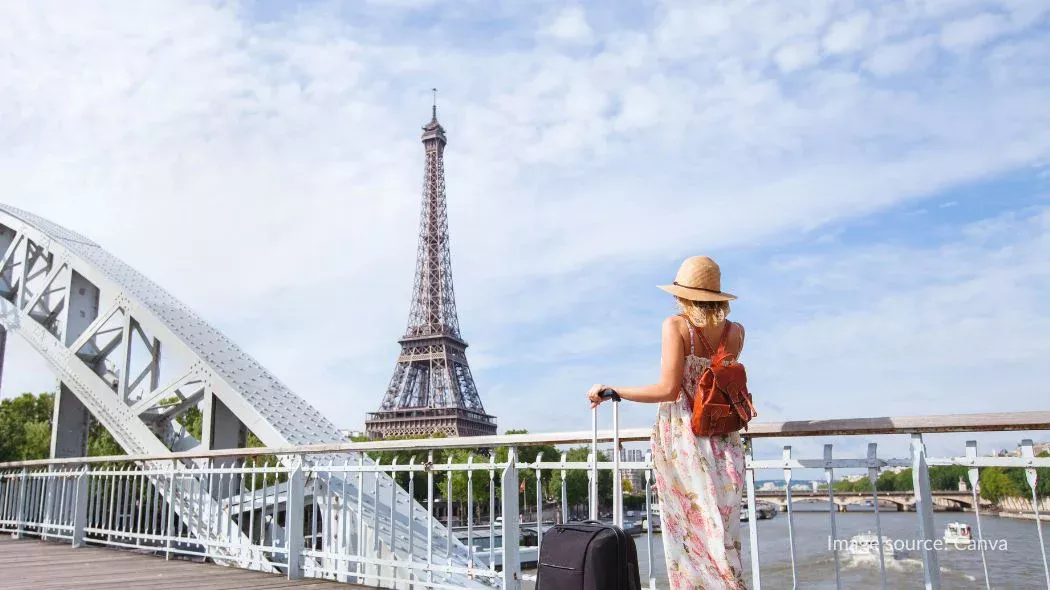 Seorang turis wanita melihat Menara Eiffel dari dekat