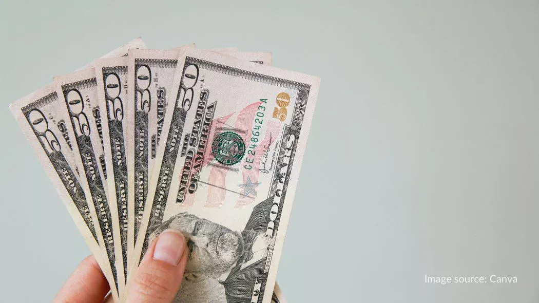 Memegang beberapa lembaran uang dollar